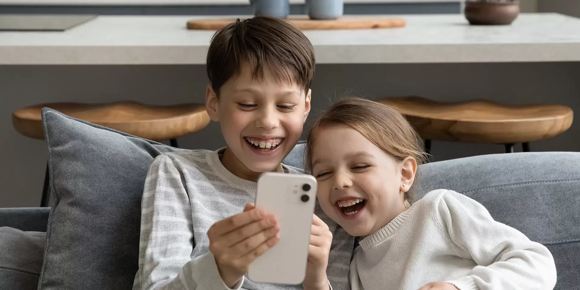 Twee jonge kinderen achter een telefoon